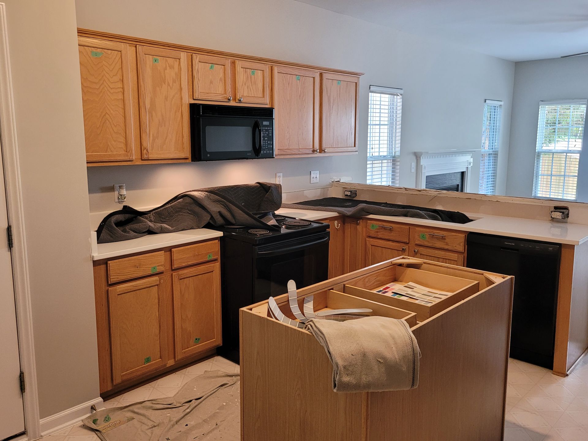Kitchen under renovation with unfinished wood cabinets, black stove, and a sink island in the foreground
