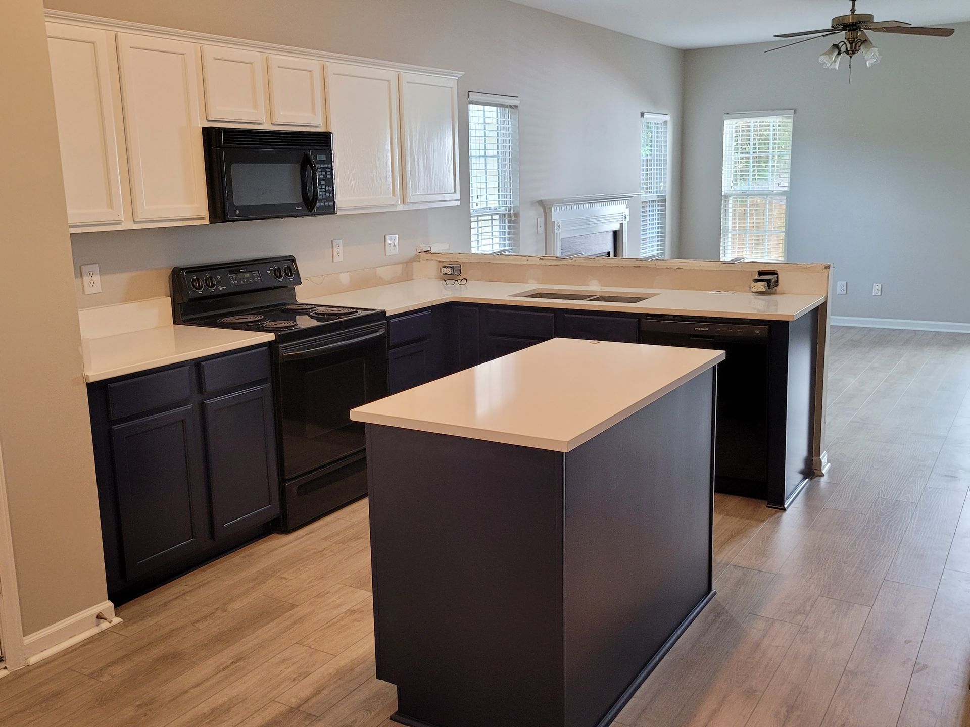 Modern kitchen with white cabinets, black appliances, and a central island in an open living area