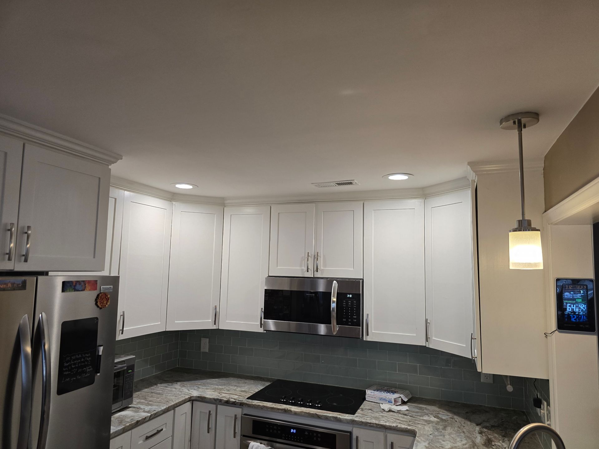 White modern kitchen with curved cabinets, stainless appliances, and pendant lighting