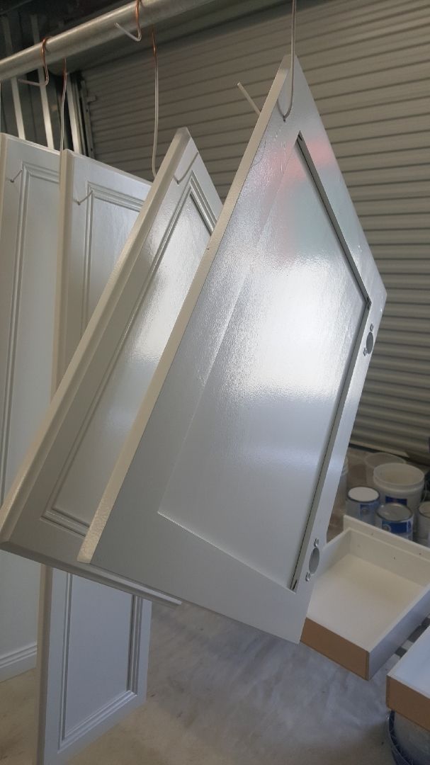 Several white cabinet doors leaning upright in a workshop-like room