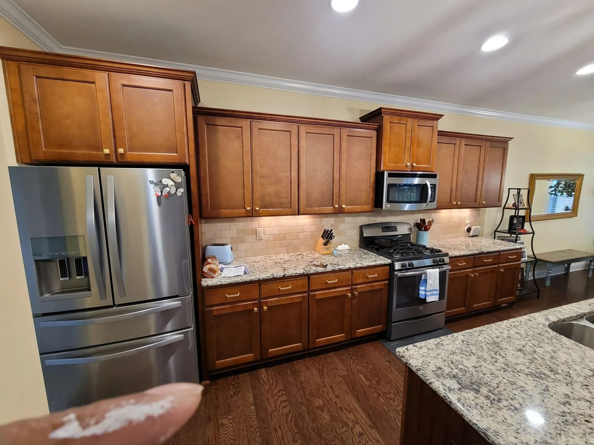 Spacious kitchen with stainless steel appliances, wood cabinets, and a granite countertop.