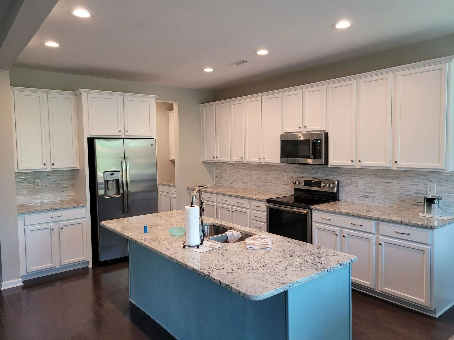 Modern kitchen with white cabinets, stainless appliances, and a large granite island