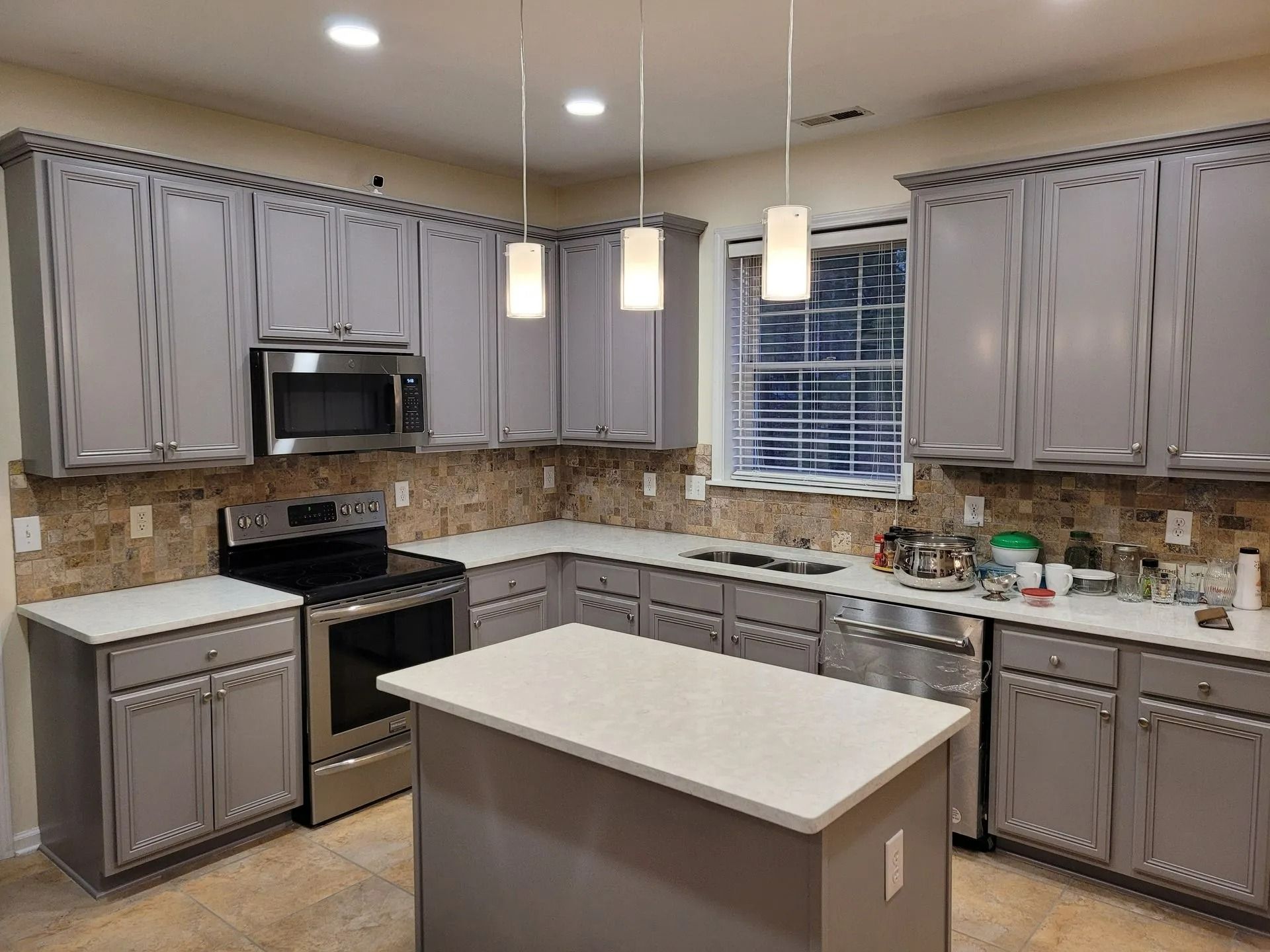Modern kitchen with gray cabinets, white island, and hanging pendant lights
