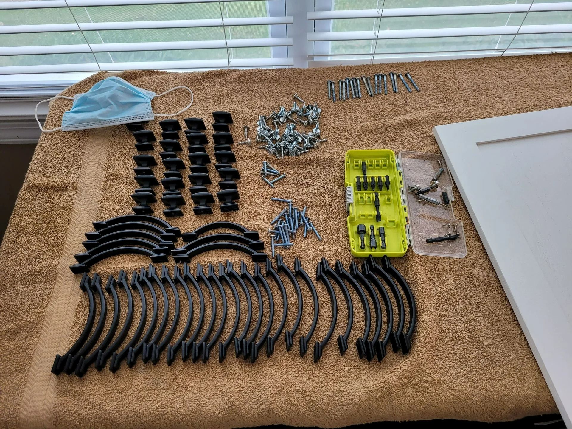 Assorted black firearm parts, magazines, and accessories laid out on a tabletop with a yellow tool case.