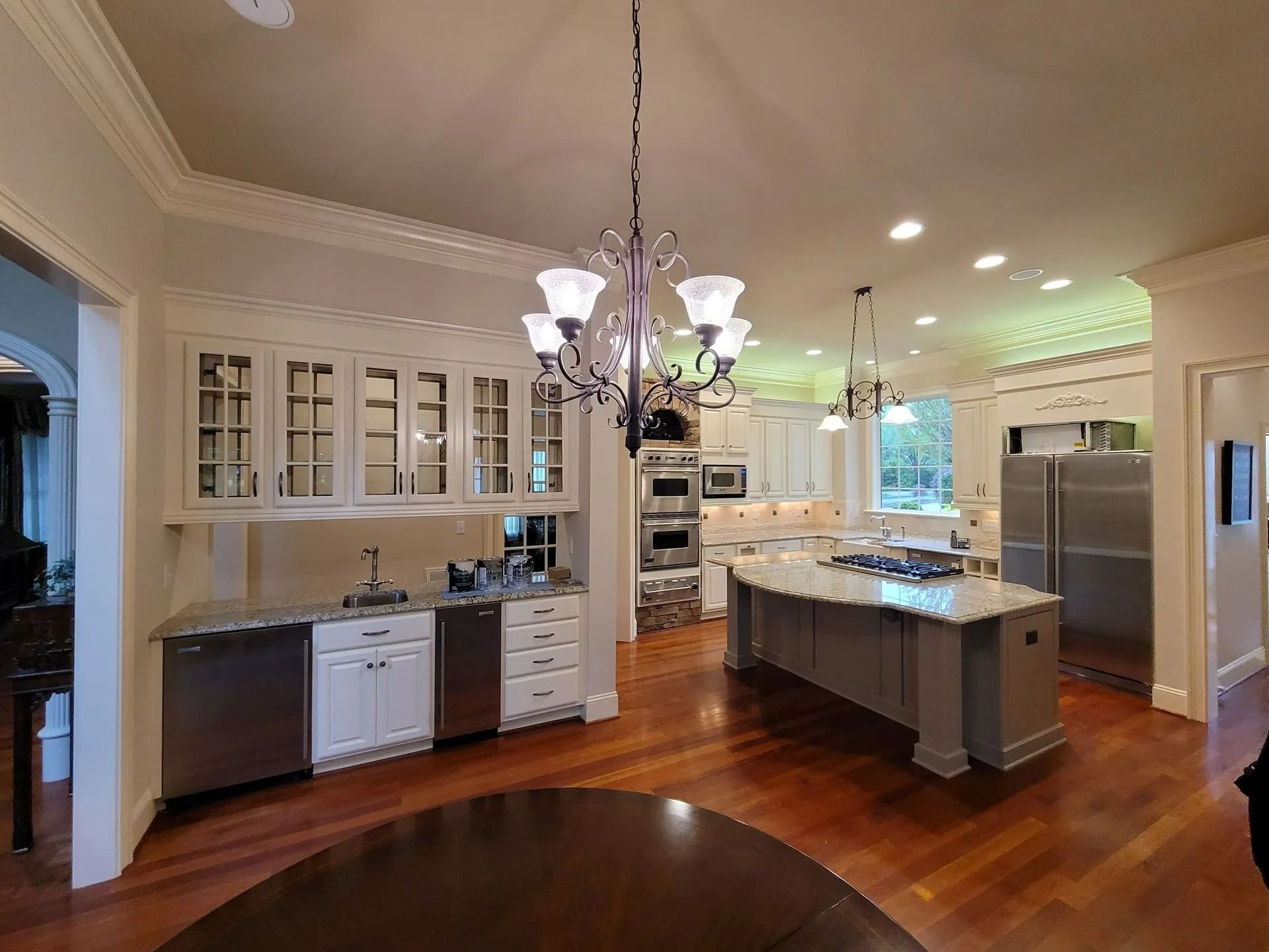 Bright gourmet kitchen with white cabinets, island, stainless steel appliances, and hardwood floors