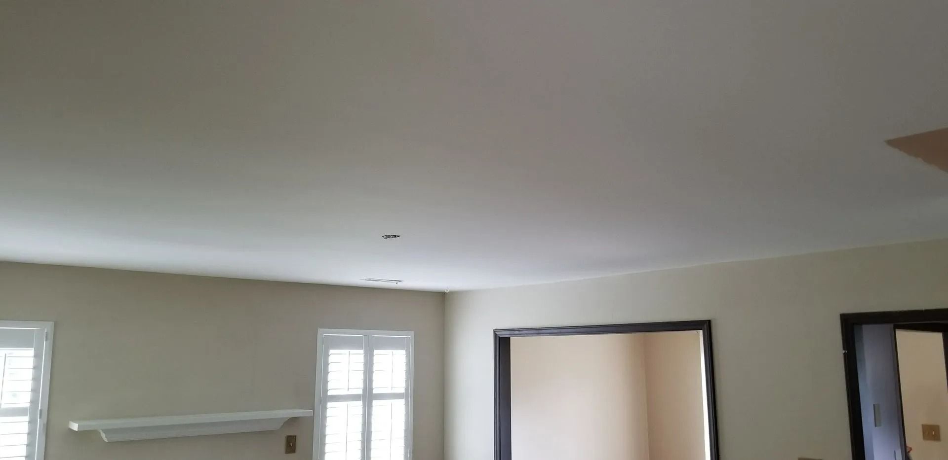 Empty room with beige walls, white ceiling, windows, and a doorway