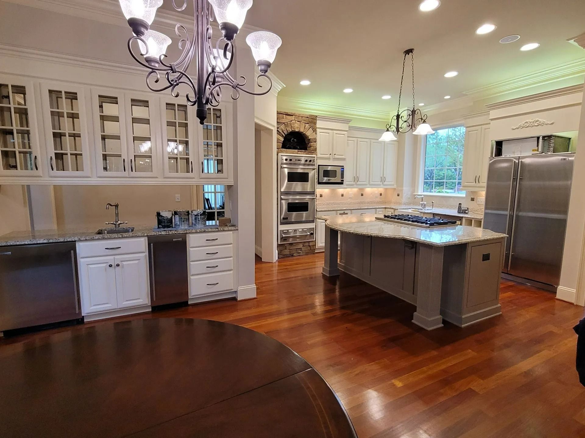 Bright, spacious kitchen with white cabinets, stainless steel appliances, hardwood floors, and a central island.