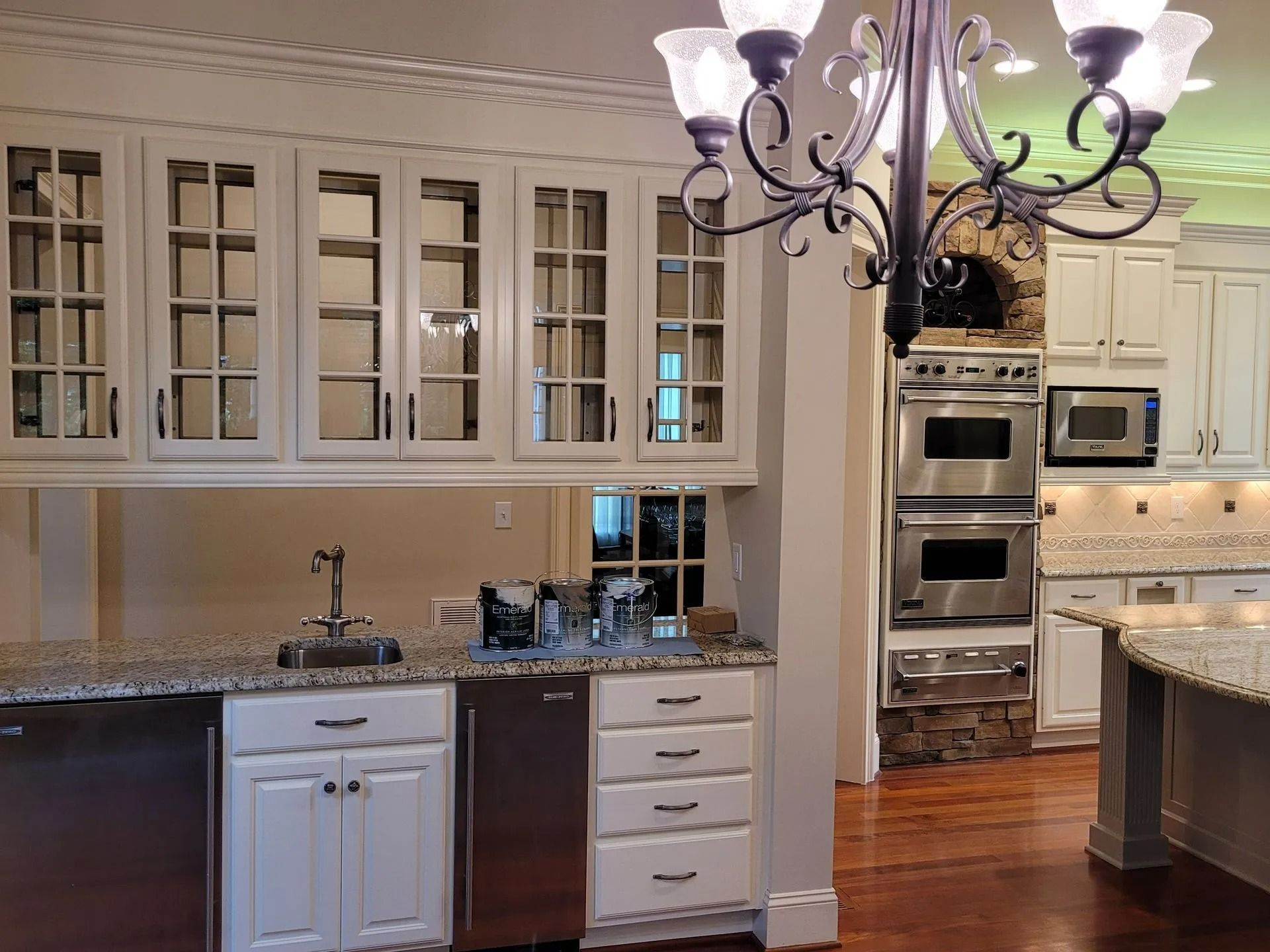 Bright kitchen with white cabinets, granite counters, stainless appliances, and a hanging chandelier