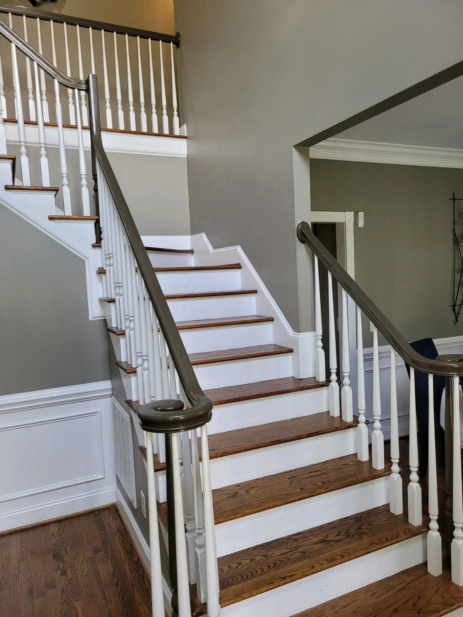Interior staircase with white railing, wooden steps, and beige walls in a home