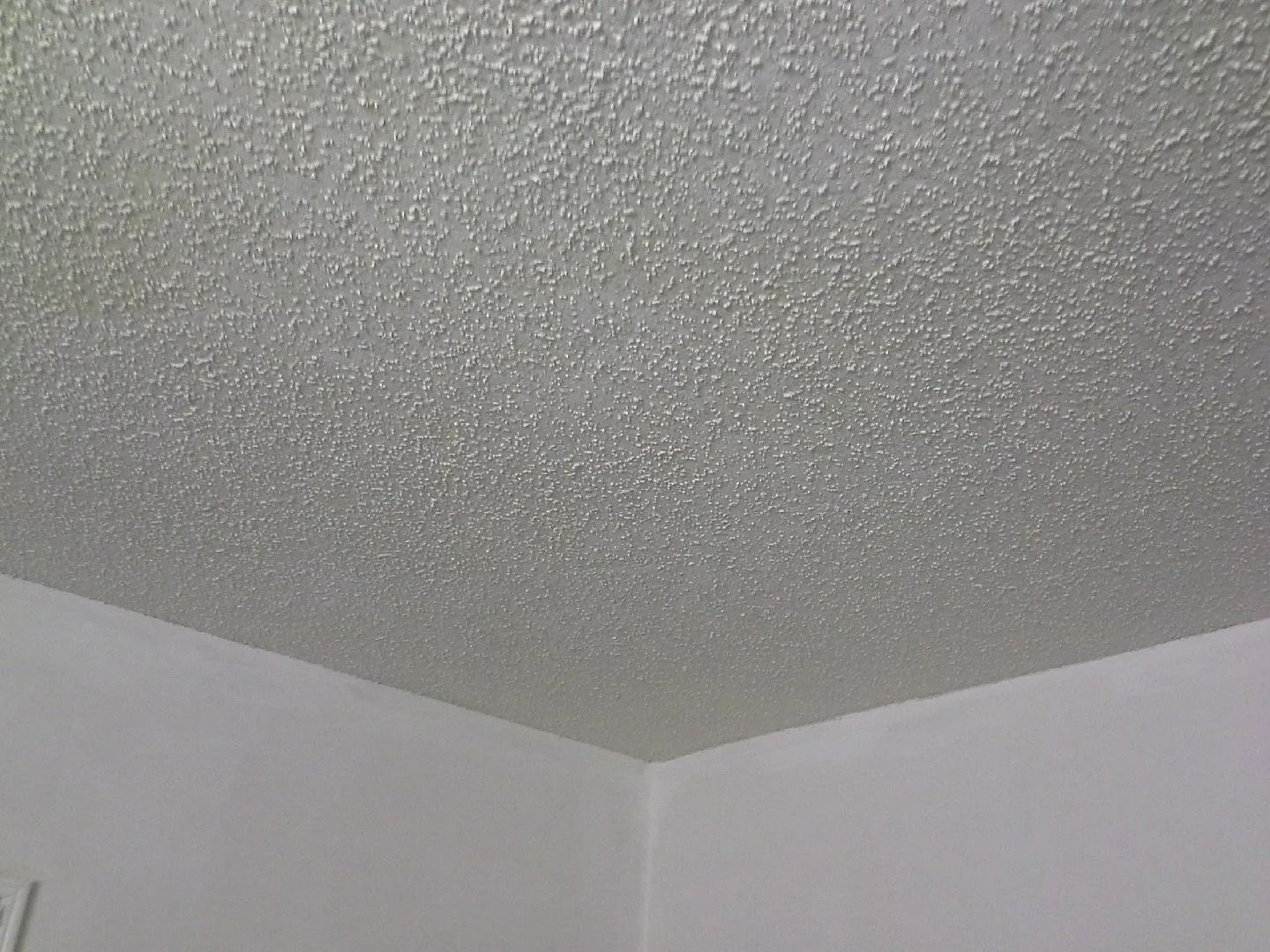 Textured white ceiling meeting pale walls in a corner of a room