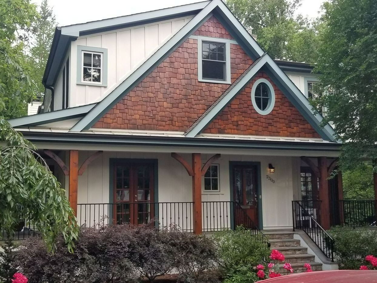 Two-story house with white siding, red brick gable, porch, and front garden