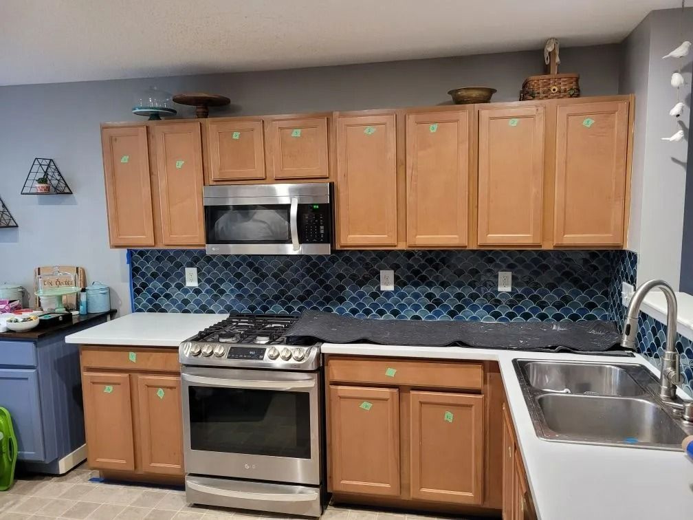 Modern kitchen with wood cabinets, stainless appliances, blue tile backsplash, and a double sink