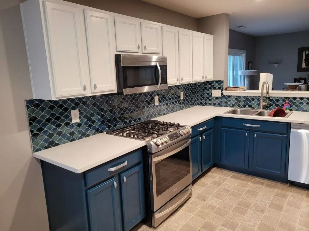 Blue-and-white kitchen with white cabinets, stainless stove, and tiled backsplash