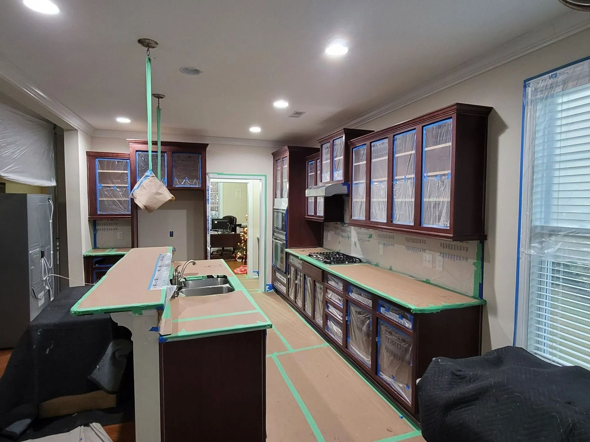 Modern kitchen with dark wood cabinets, green countertops, island, and hanging light fixture