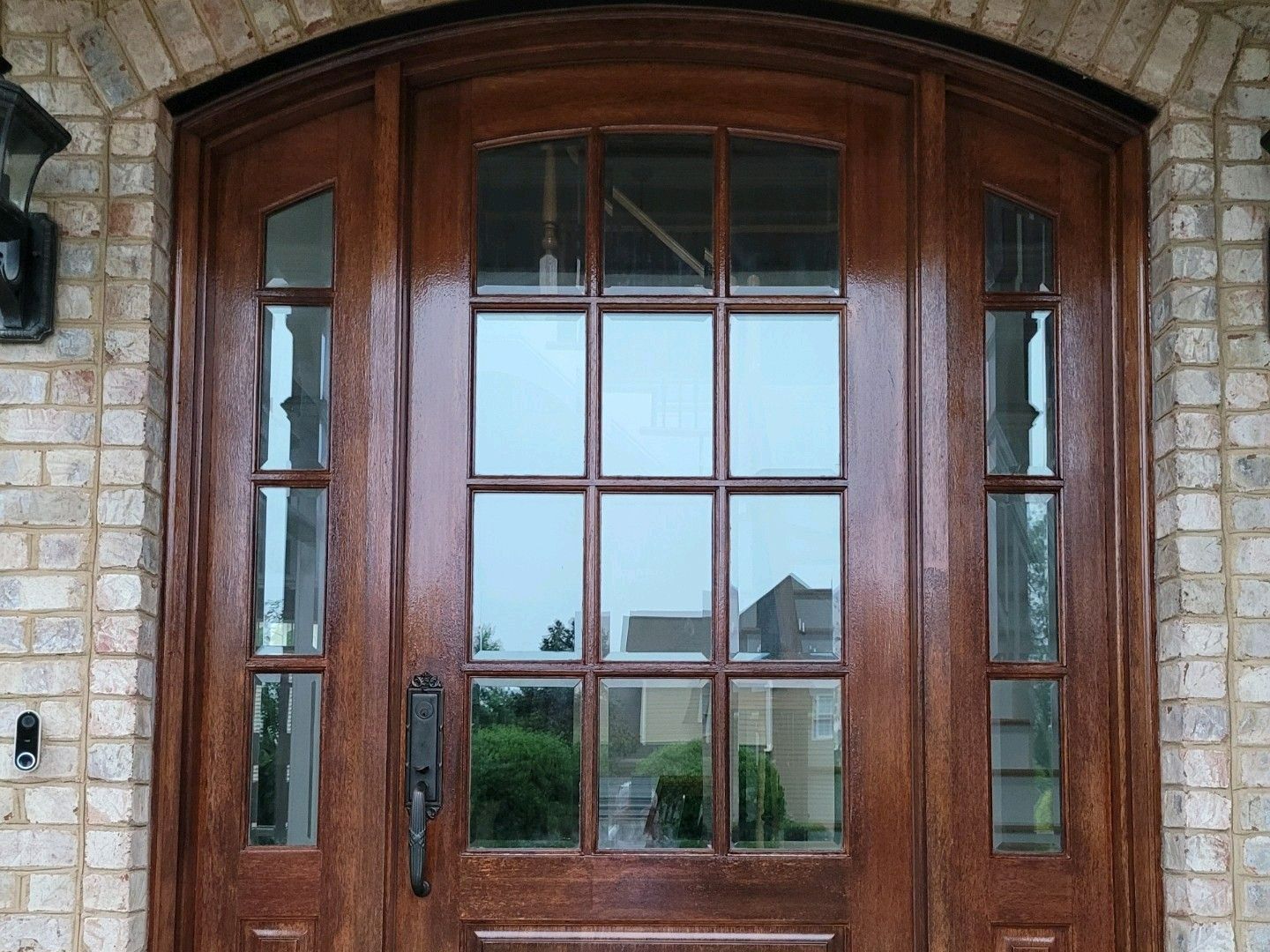 Wooden arched double front door with glass panes set in a stone brick entryway