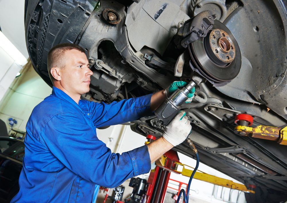 A Man is Working on the Underside of a Car in a Garage — Mechanical World In Wagga Wagga, NSW