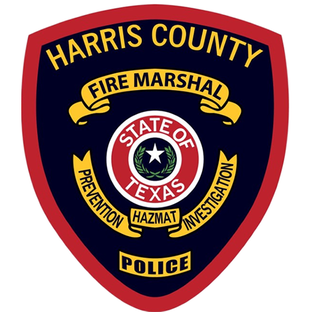 The Harris County Fire Marshal badge, a shield-shaped emblem in red, blue, and gold featuring the State of Texas seal.