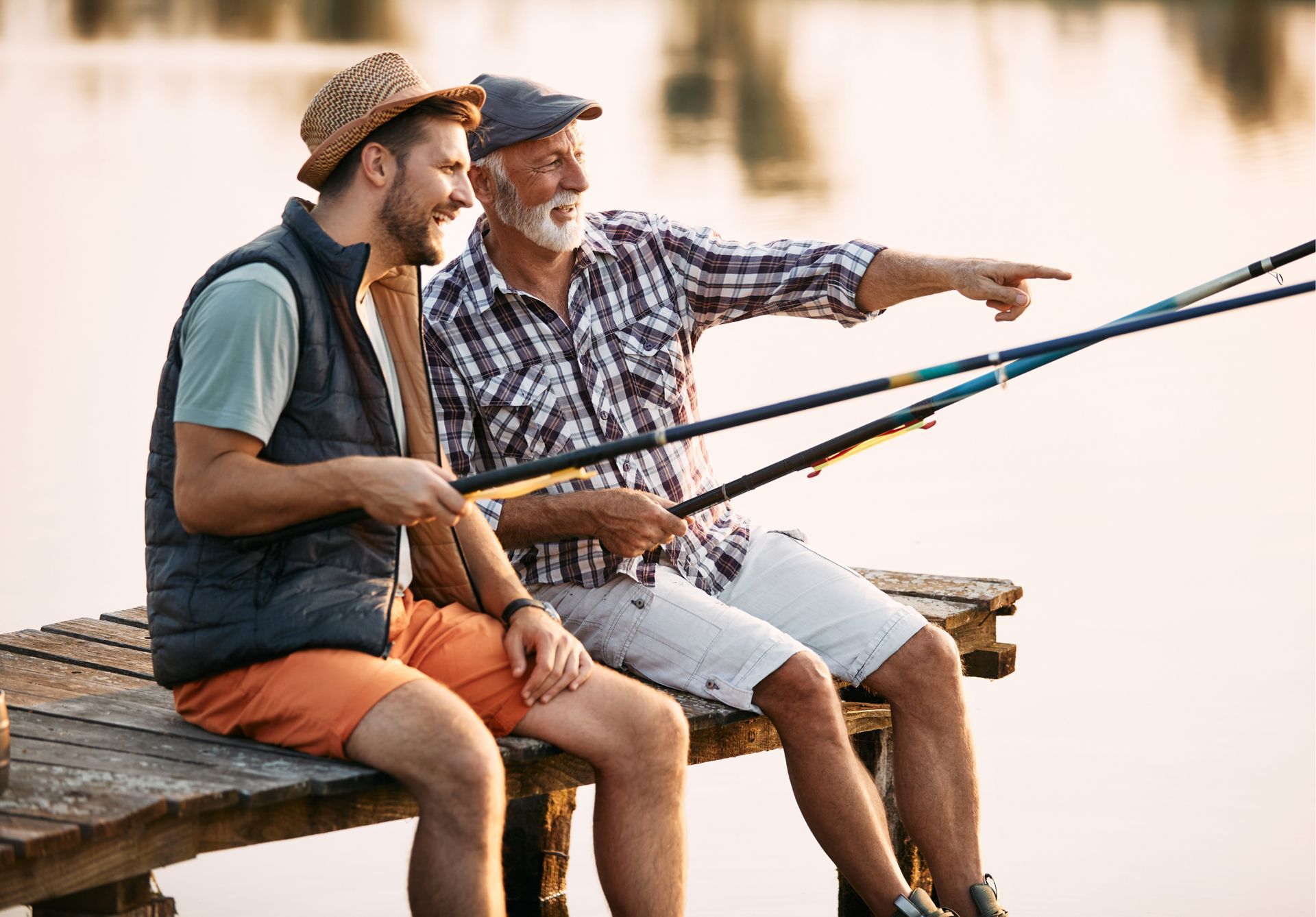 Two men are sitting on a dock fishing.