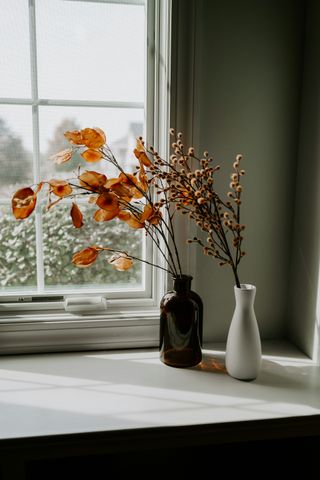 A vase of flowers is sitting on a window sill next to a window.