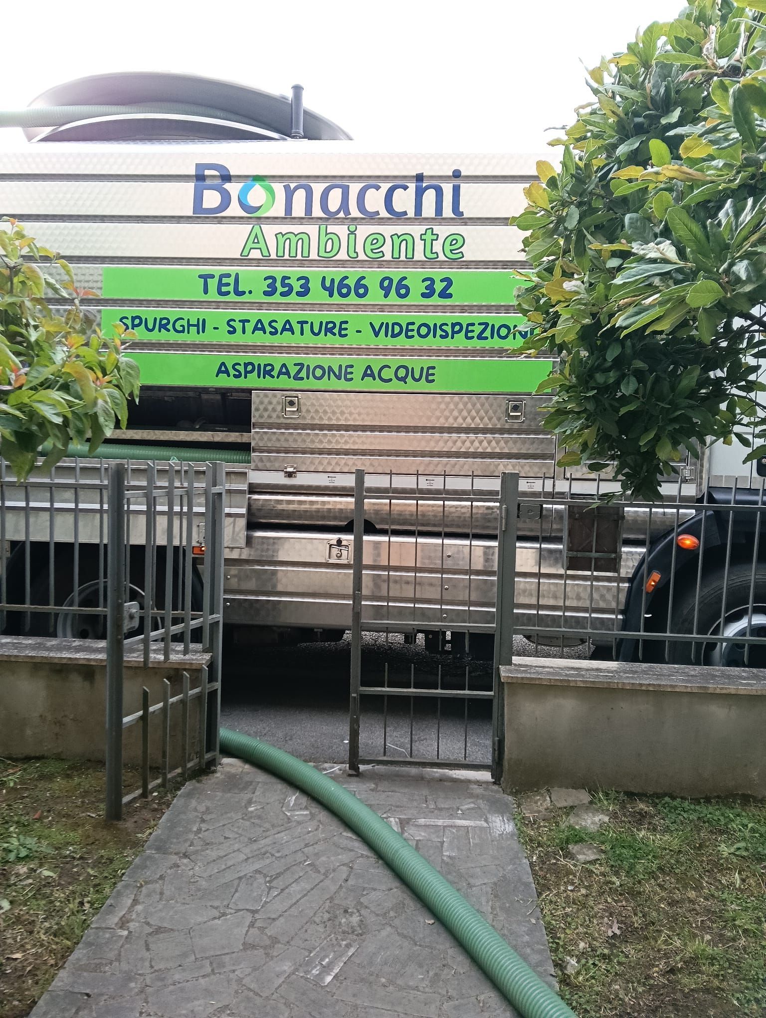 Cartello per il centro assistenza Bonacchi con cancello verde e tubo flessibile davanti a un vialetto d'accesso.