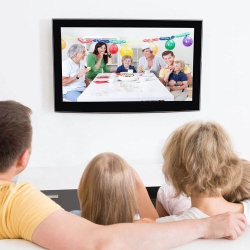 A family is watching a birthday party pictures on a television