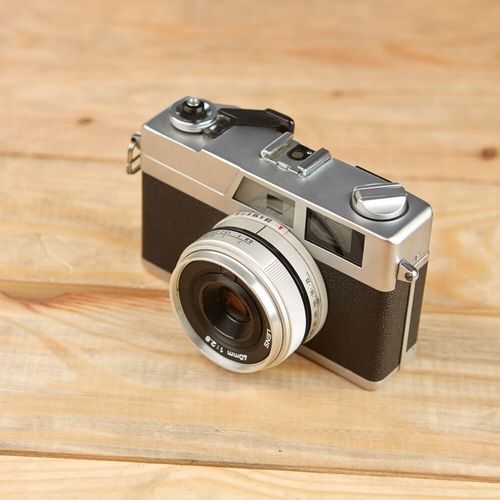An old camera is sitting on a wooden table.
