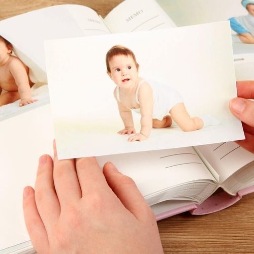 A person is holding a picture of a baby in a book