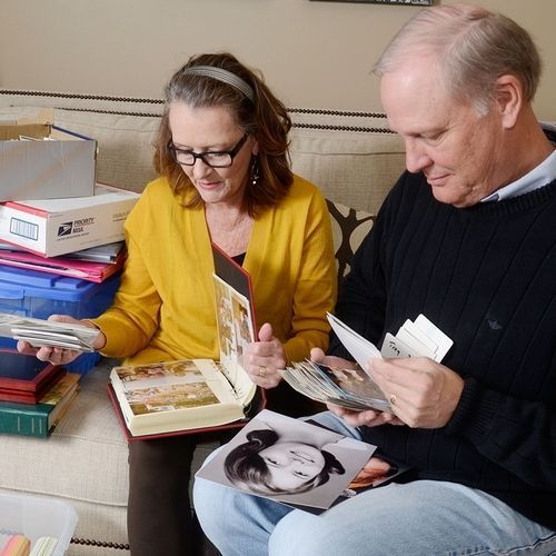 A man and a woman are sitting on a couch looking at pictures