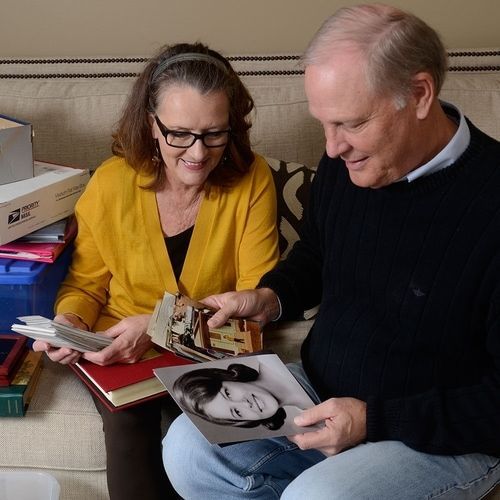 A man and a woman are sitting on a couch looking at pictures