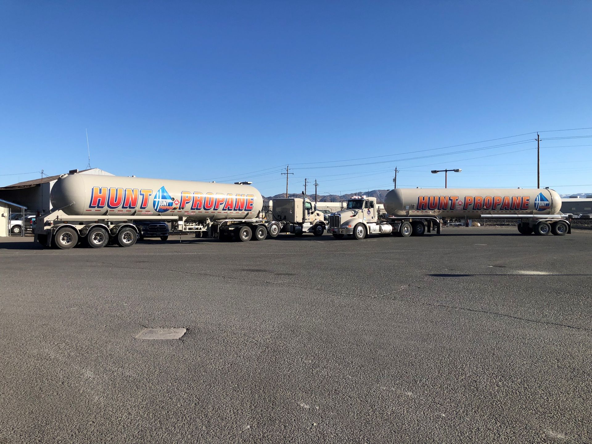 A tanker truck is driving down a road with trees in the background.