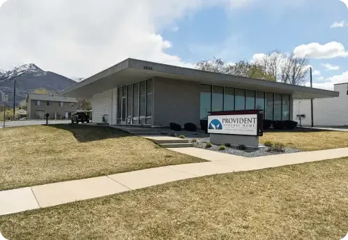 Modern medical clinic building with a sign, on a grassy corner under a partly cloudy sky
