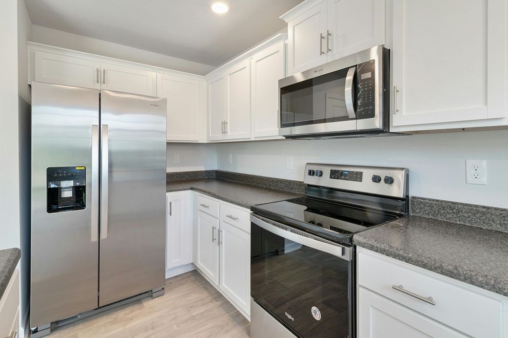 Modern kitchen with white cabinets, stainless steel appliances, and gray granite countertops.