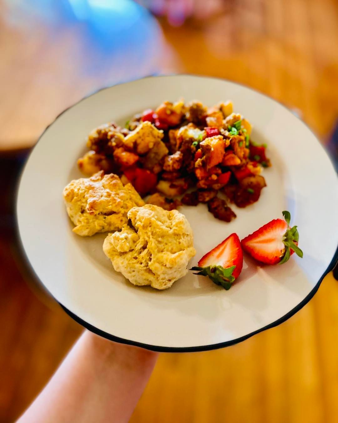 A person is holding a plate of food with strawberries on it