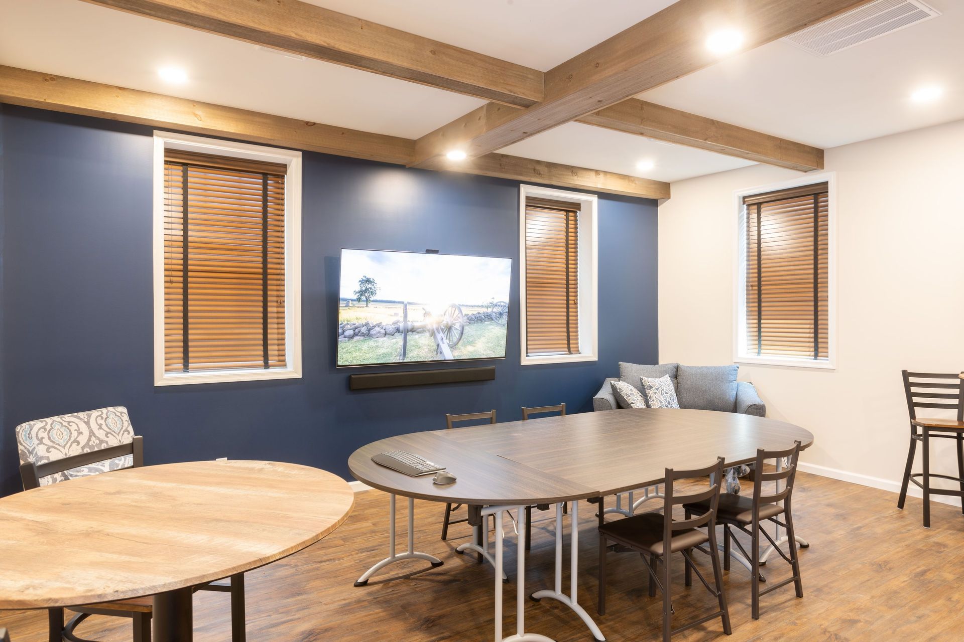 A conference room with tables and chairs and a flat screen tv on the wall.
