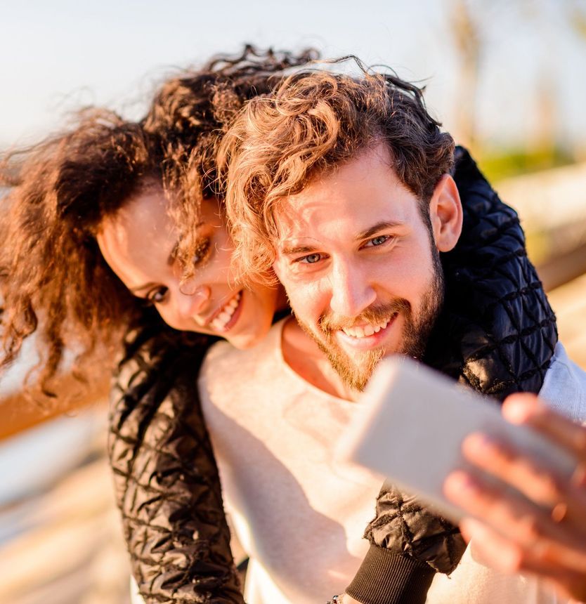A man and a woman are taking a selfie with a cell phone.
