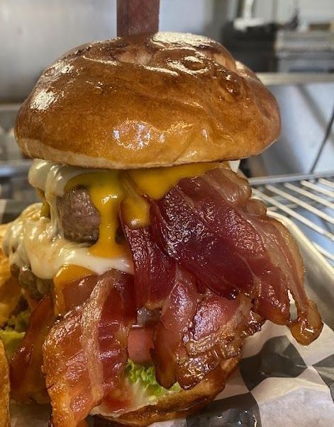 A close up of a hamburger with bacon and cheese on a bun.