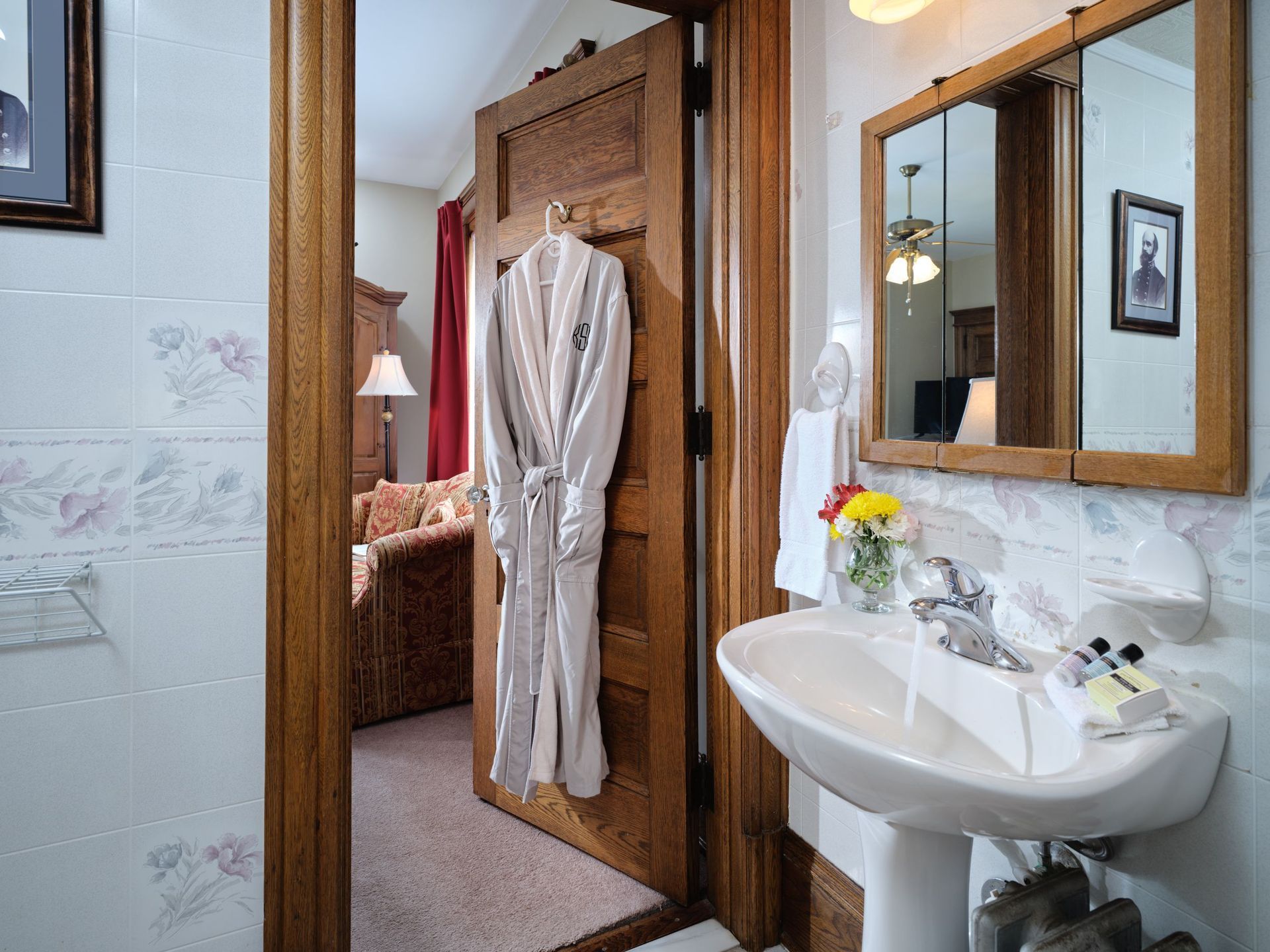 A bathroom with a sink , mirror and robe hanging on the door.