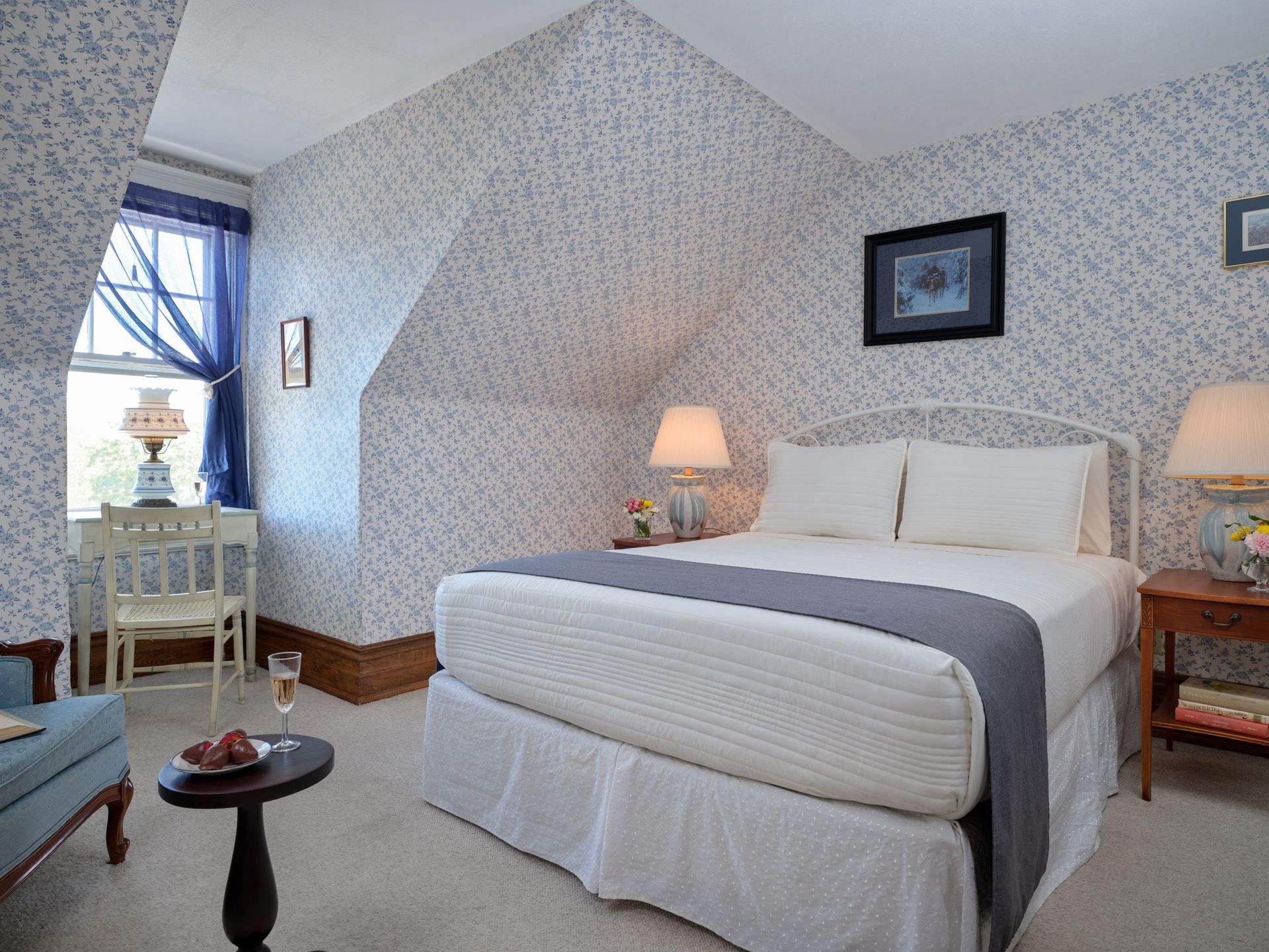 A bedroom with a king size bed and a table with a glass of wine on it.