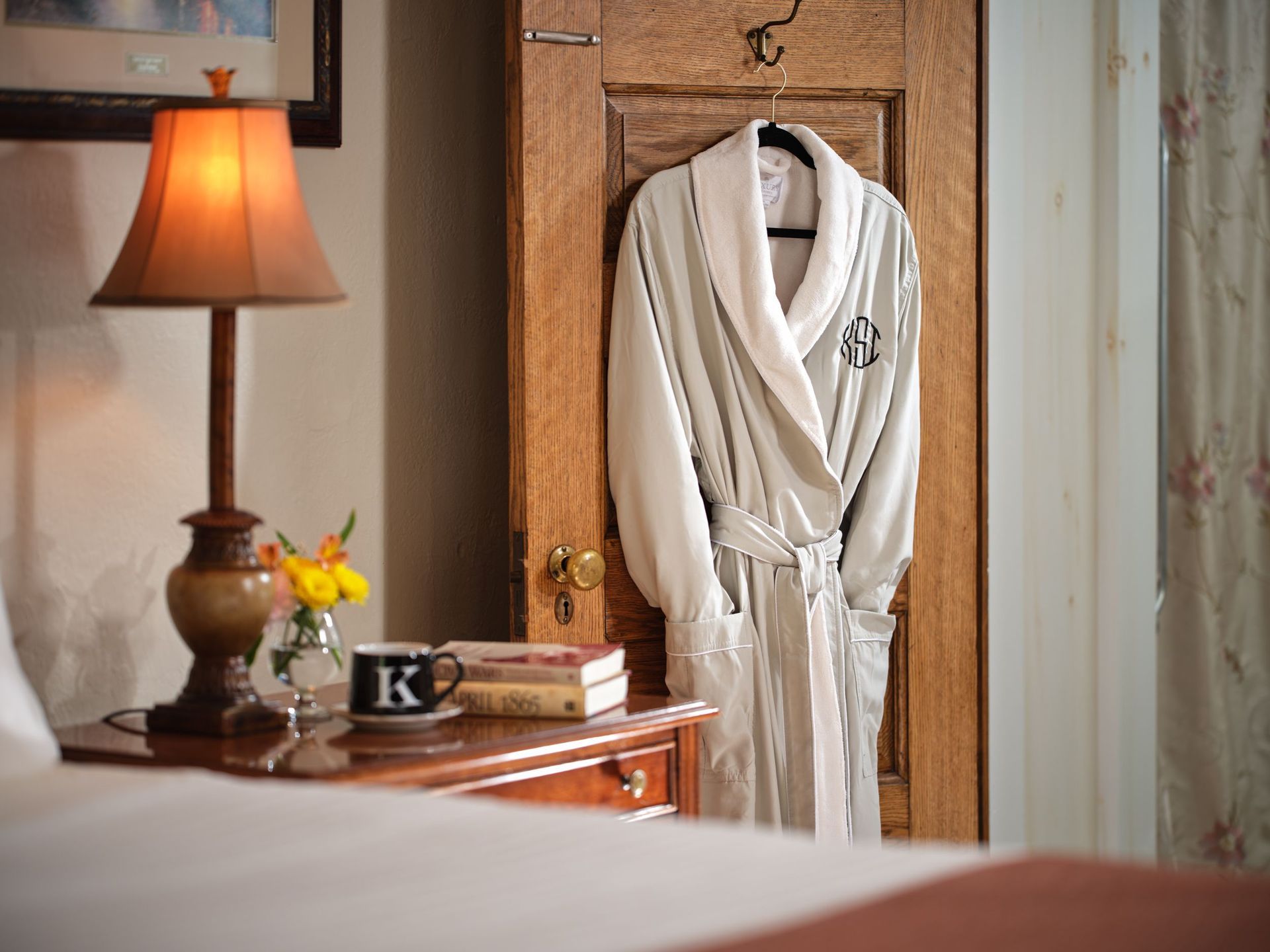 A robe is hanging on a wooden door next to a lamp.