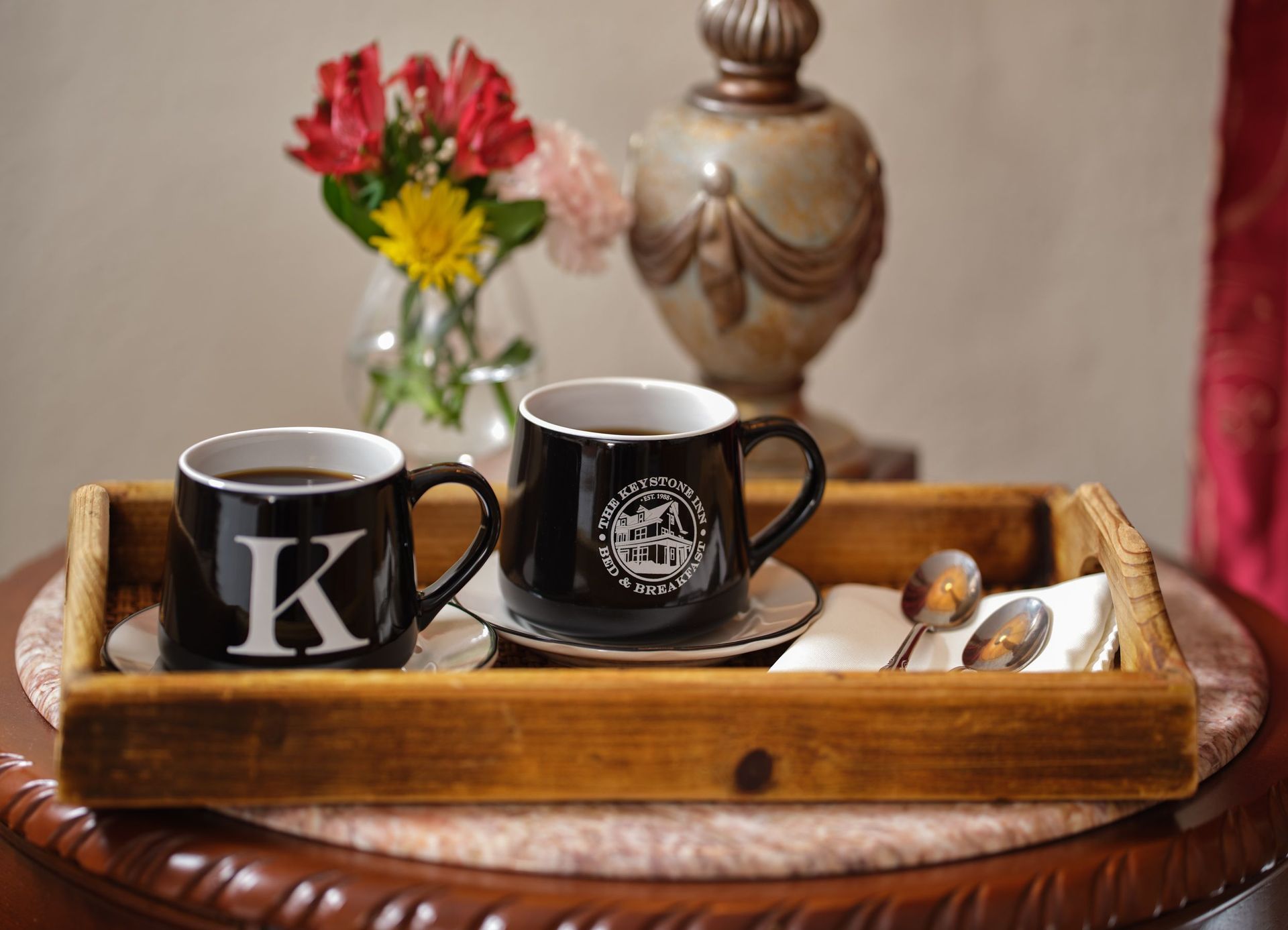 Two cups of coffee on a wooden tray with the letter k on them