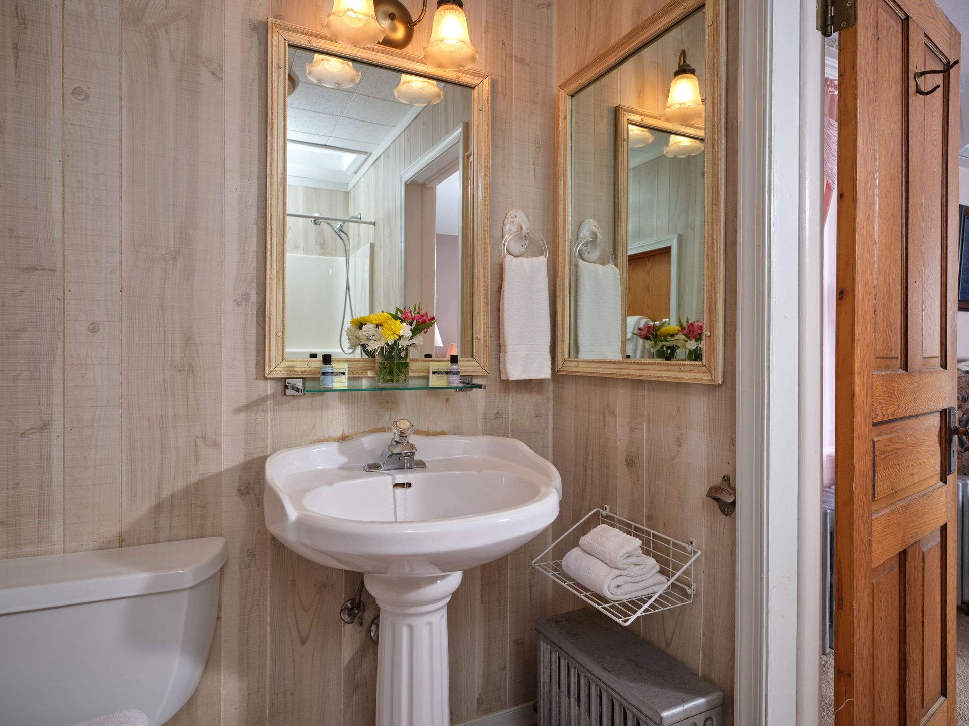 A bathroom with a sink , toilet and two mirrors.