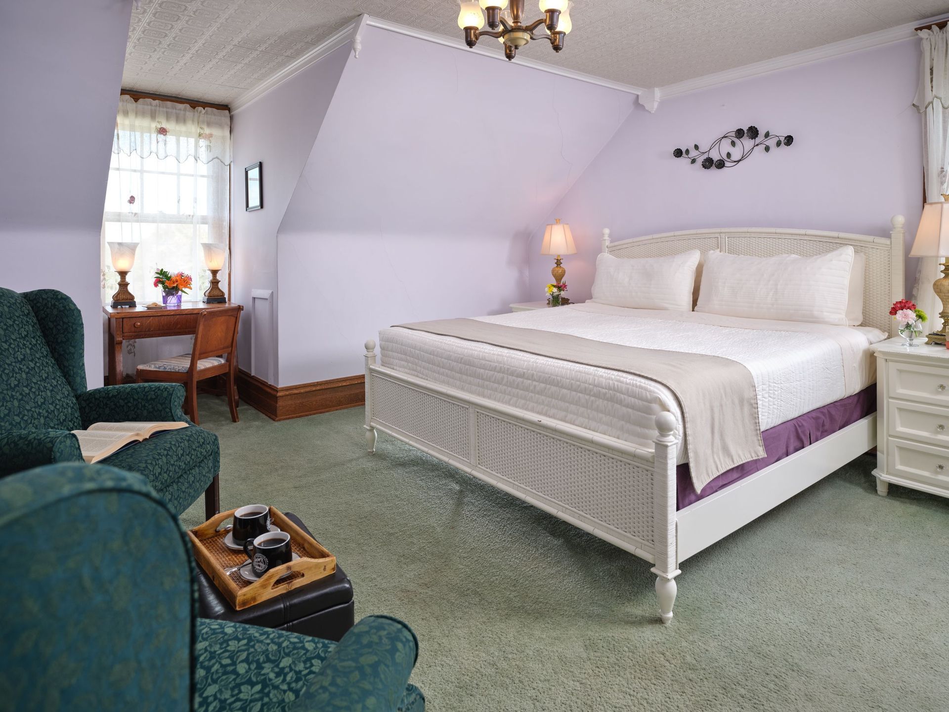 A bedroom with a king size bed , chair , desk and nightstand.