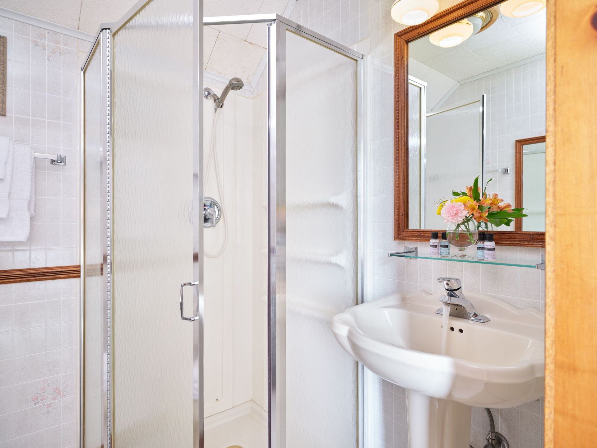 A bathroom with a sink , shower and mirror.