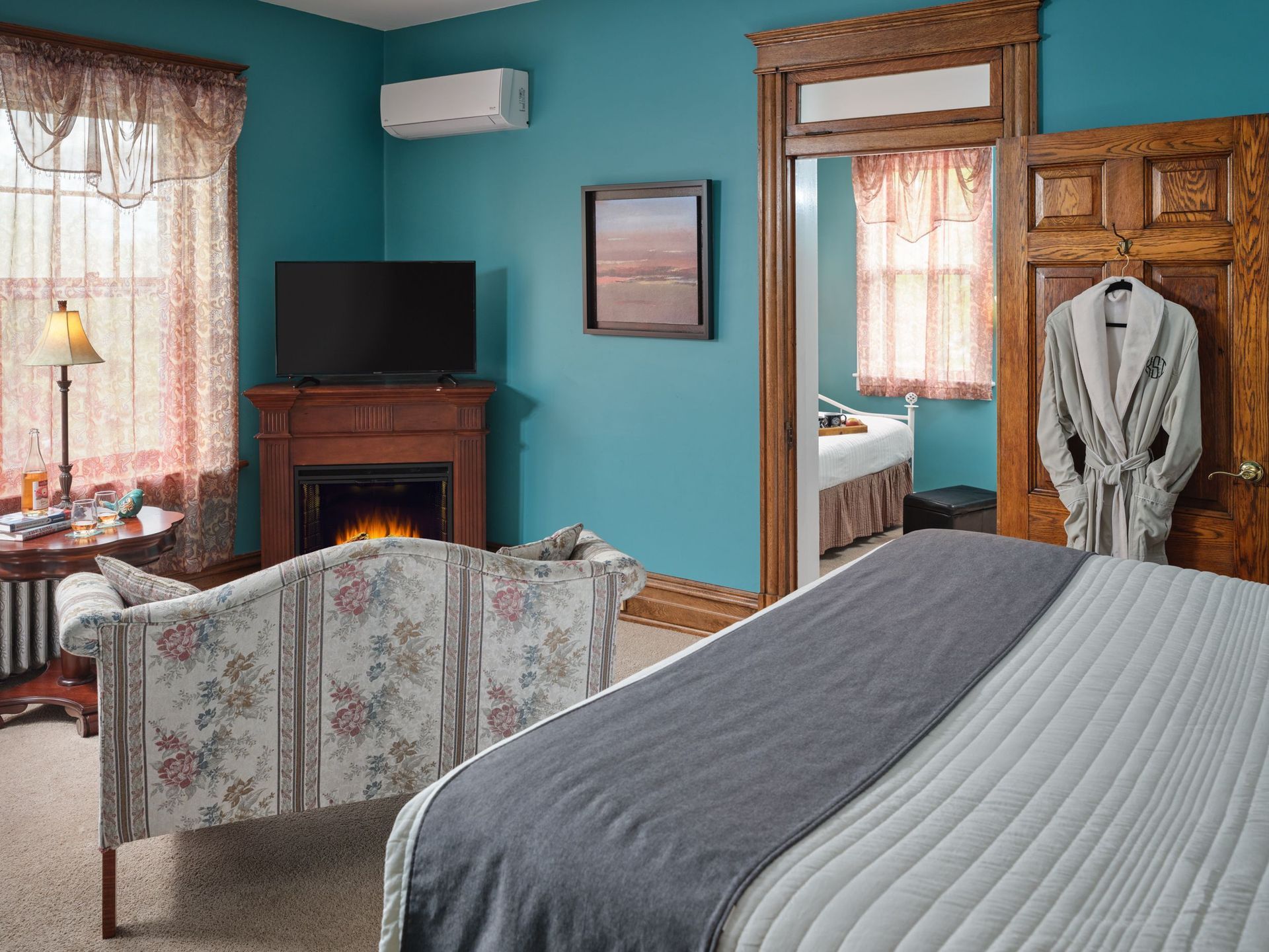 A bedroom with a bed , couch , television and fireplace.