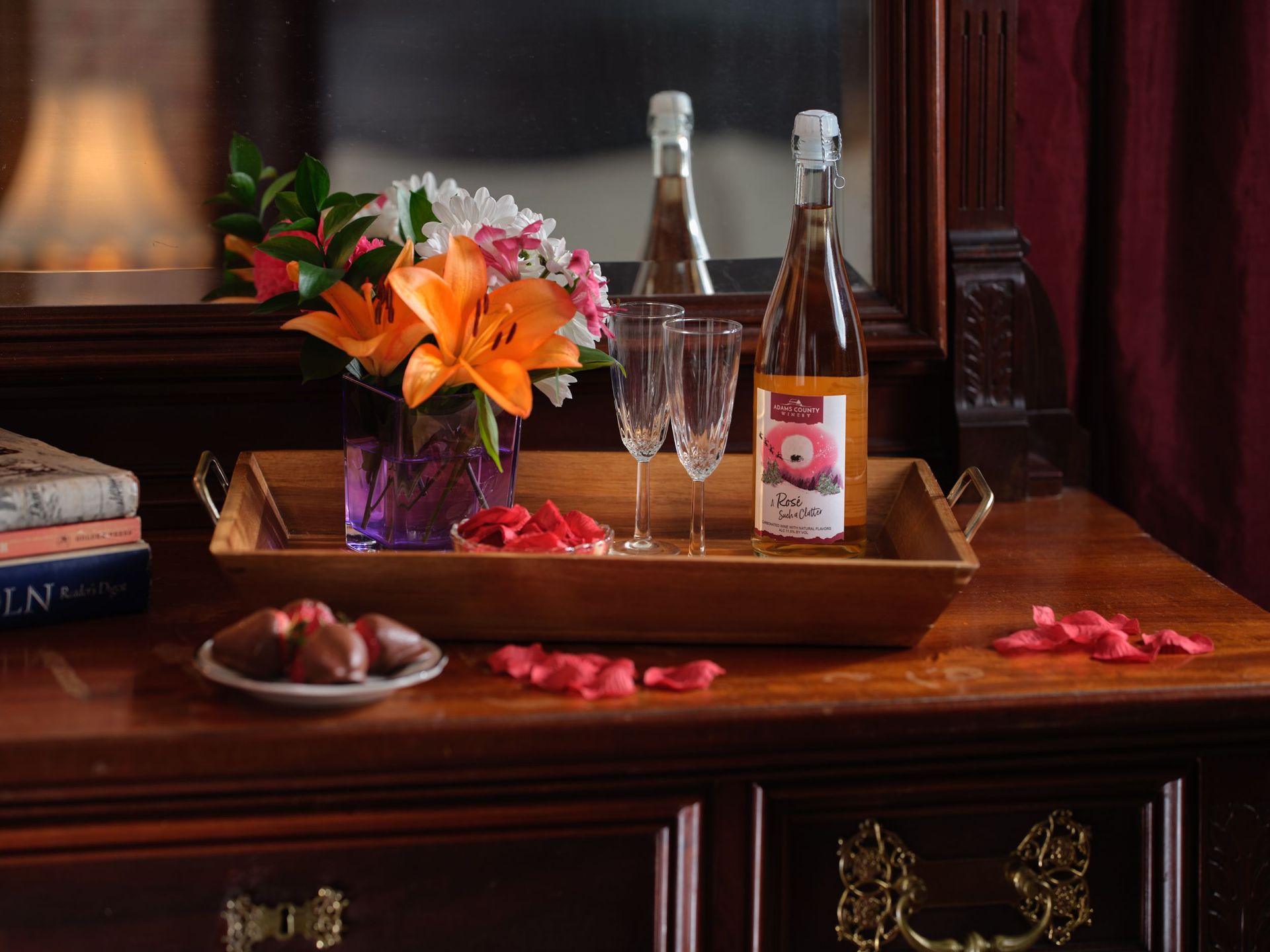 Two bottles of wine are on a wooden tray on a table.