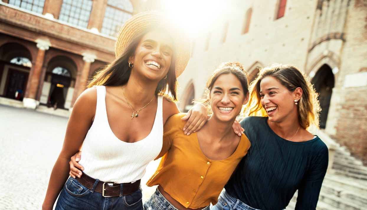 Three women are standing next to each other on a city street.