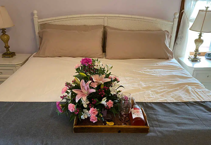 A bed with a tray of flowers and wine on it