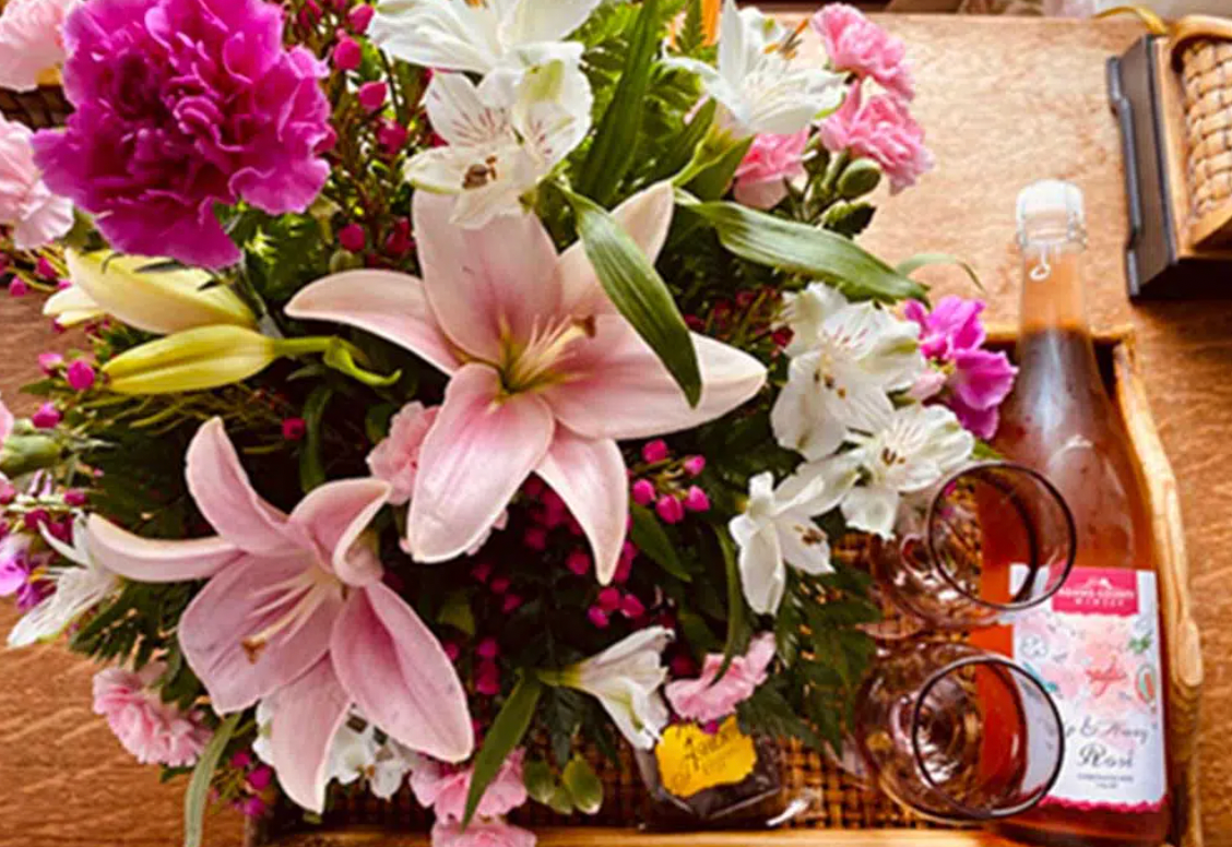 A tray with flowers and a bottle of wine on it.