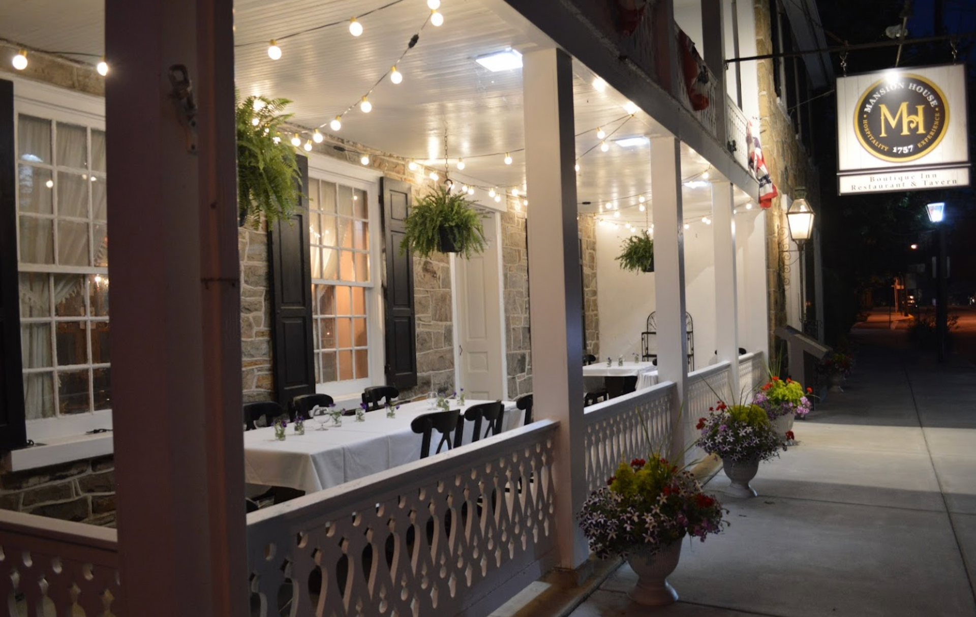 A restaurant with tables and chairs on the porch at night