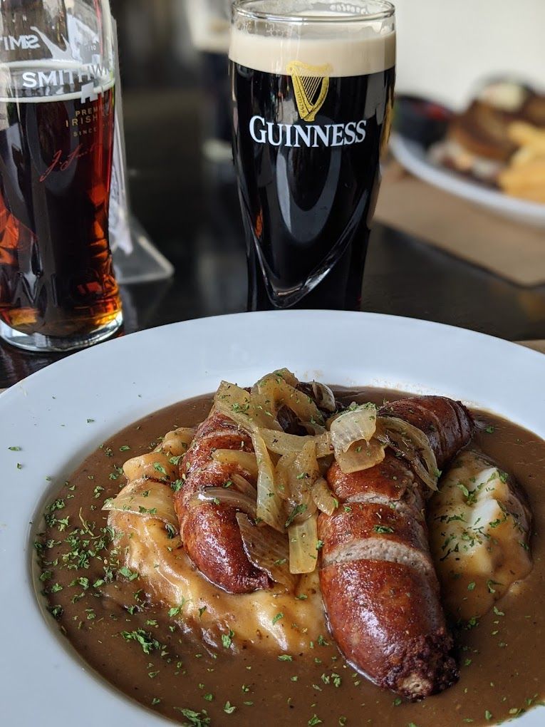 A plate of food with a glass of guinness beer in the background.